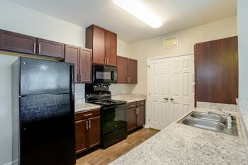 A kitchen with a black refrigerator, microwave, and stove at Cedar Terrace Apartments in Hendersonville